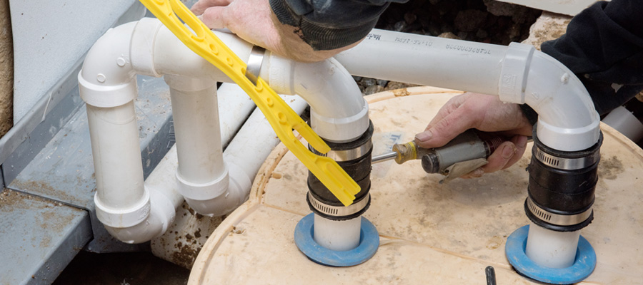 Worker tightening pipe fittings with a drill on a plumbing system.