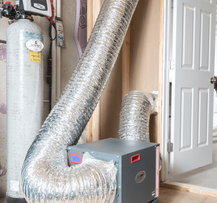 Two large, flexible HVAC ducts connected to a dehumidifier in a basement.